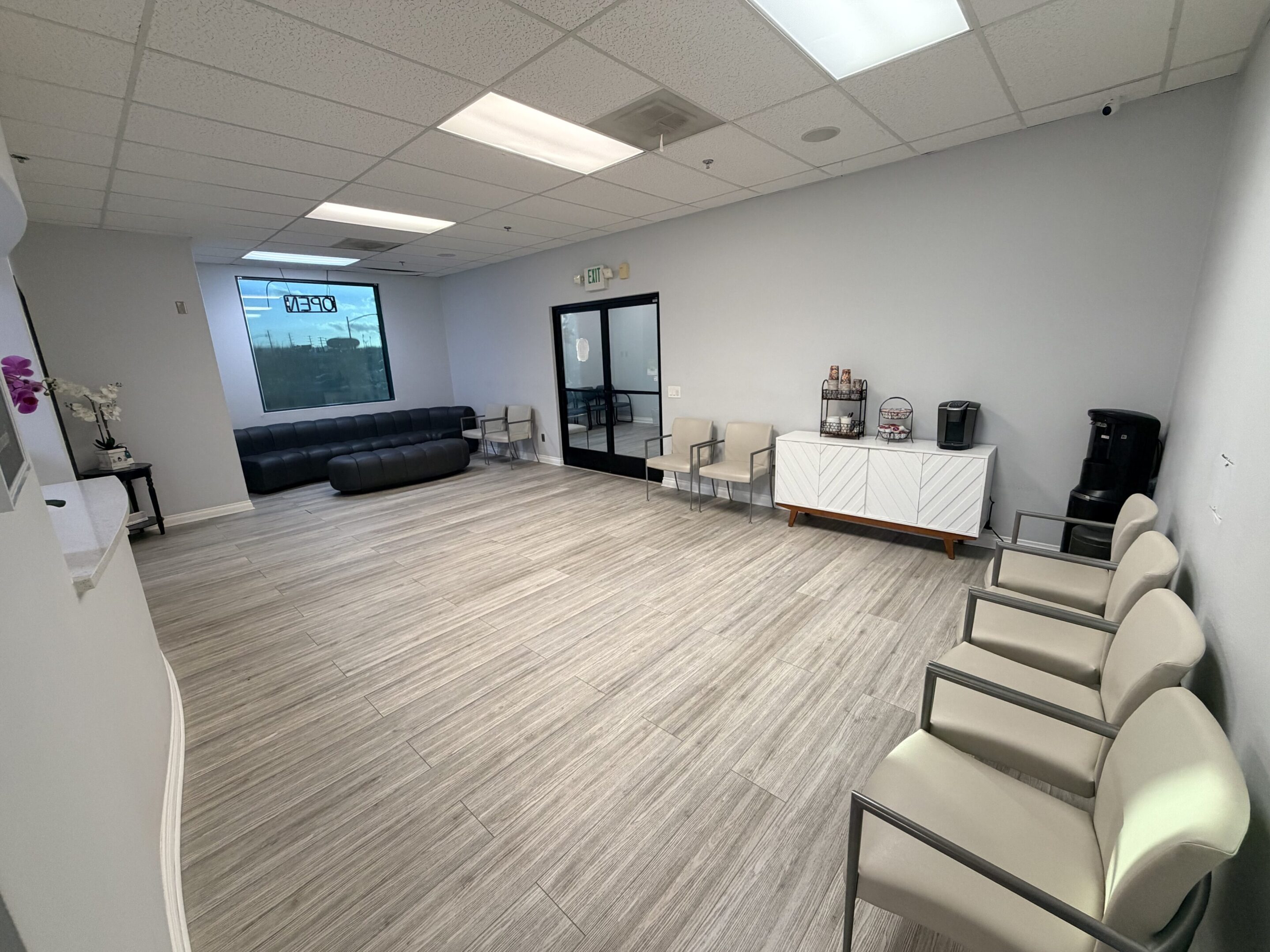 Modern waiting room with chairs, a sofa, and refreshments.